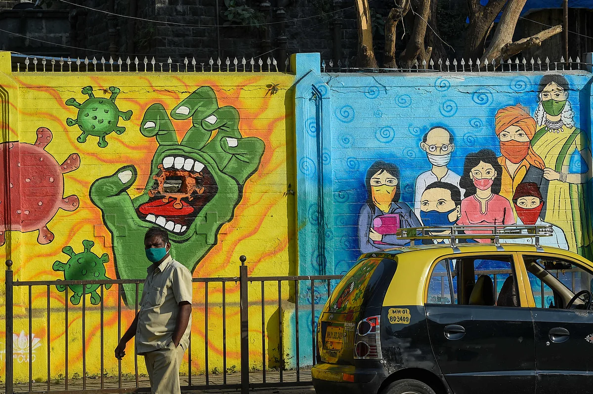 A pedestrian walks past a wall mural depcting the Covid-19 coronavirus in Mumbai on January 29, 2022.  | (Photo by Punit PARANJPE / AFP)