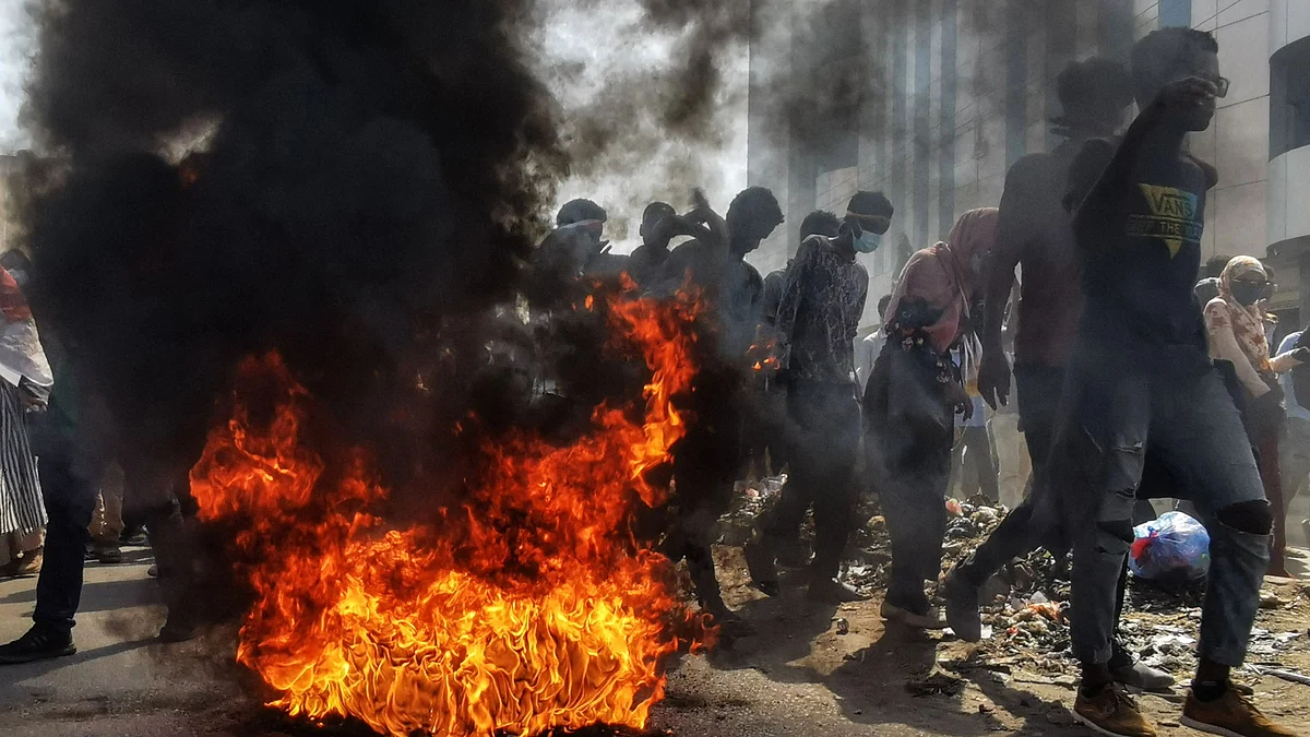 Sudanese protesters rallying against the military, walk past burning tyres in the capital Khartoum, on January 6, 2022. | (Photo by AFP)