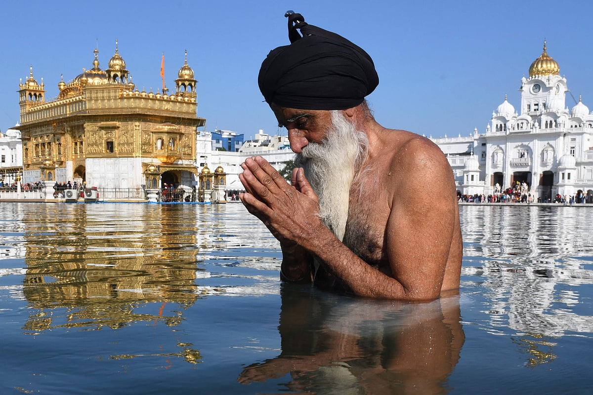 TOPSHOT - Sikh devotee takes a dip in the holy sarovar (pond) on the occasion of the birth anniversary of the 10th Sikh Guru Gobind Singh at the Golden Temple in Amritsar on January 9, 2022.