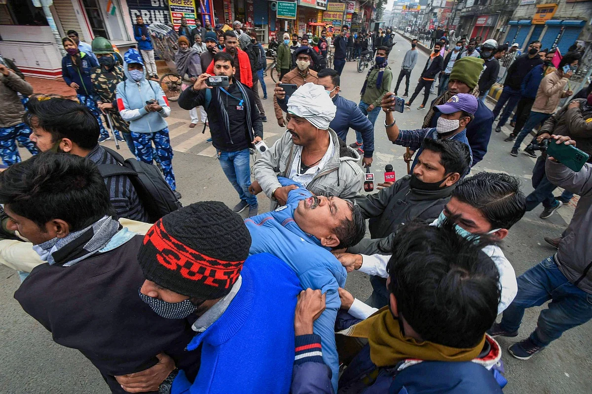 Protesters carry an injured police officer after he fell unconscious while on duty during the Bihar bandh protest over alleged erroneous results of Railway Recruitment Boards Non-Technical Popular Categories (RRB NTPC) exam, in Patna, Friday, Jan. 28, 2022.