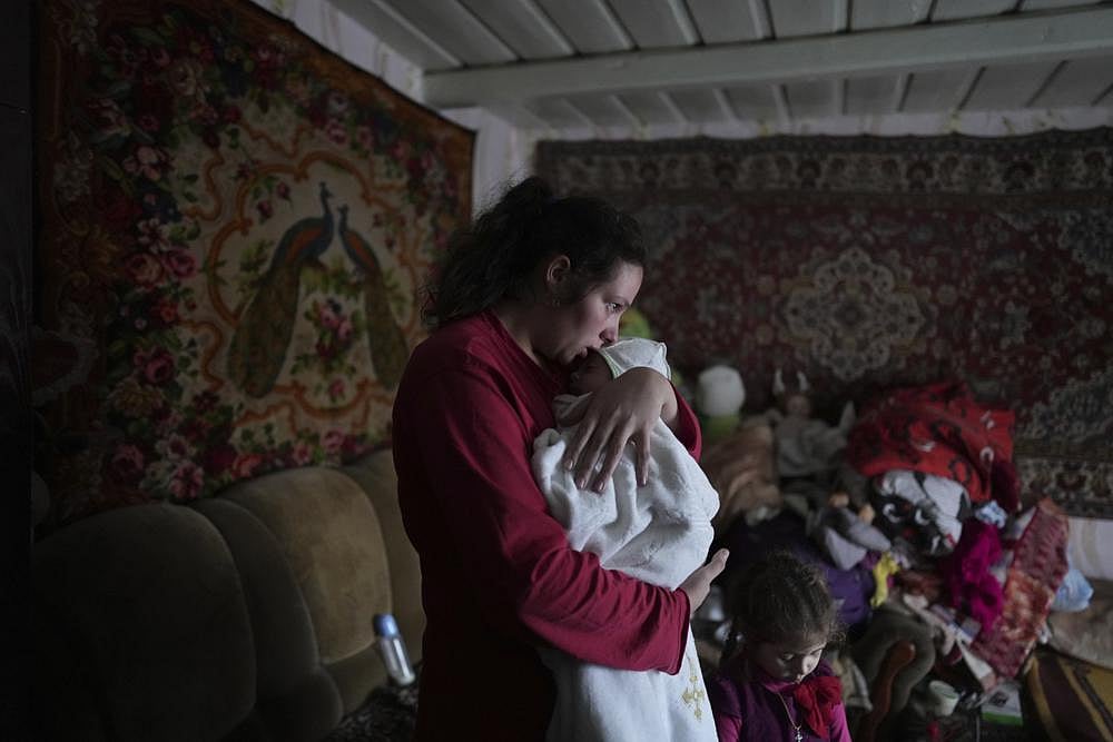 Anastasia Manha, 23, lulls her 2 month-old son Mykyta, where she lives with her family members, after alleged shelling by separatists forces in Novognativka, eastern Ukraine, on Sunday | AP