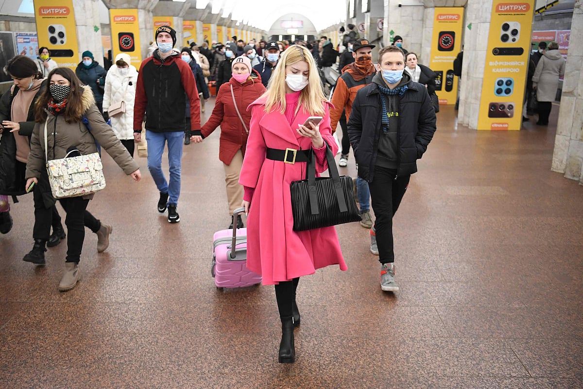 People, some carrying bags and suitcases, walk in a metro station in Kyiv early on February 24, 2022. 