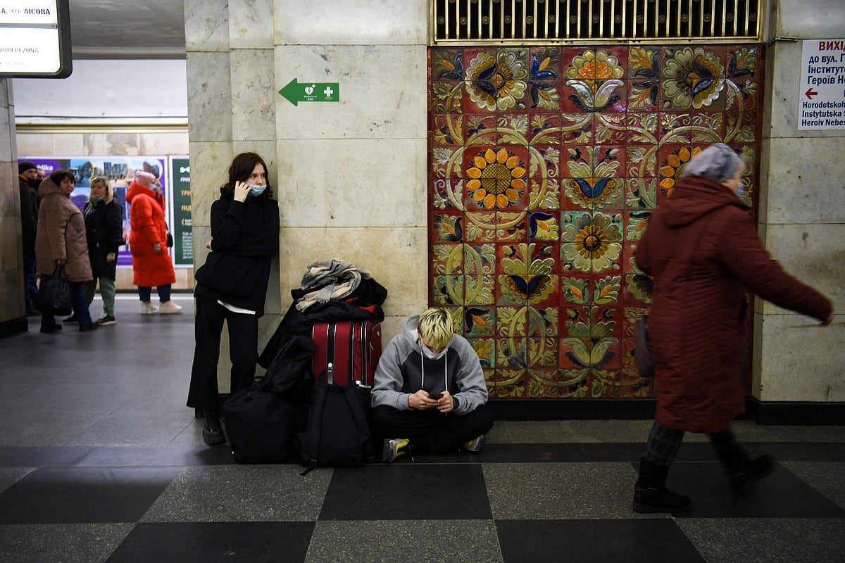 A young couple with a suitcase and bags waits at a metro station in Kyiv early on February 24, 2022.