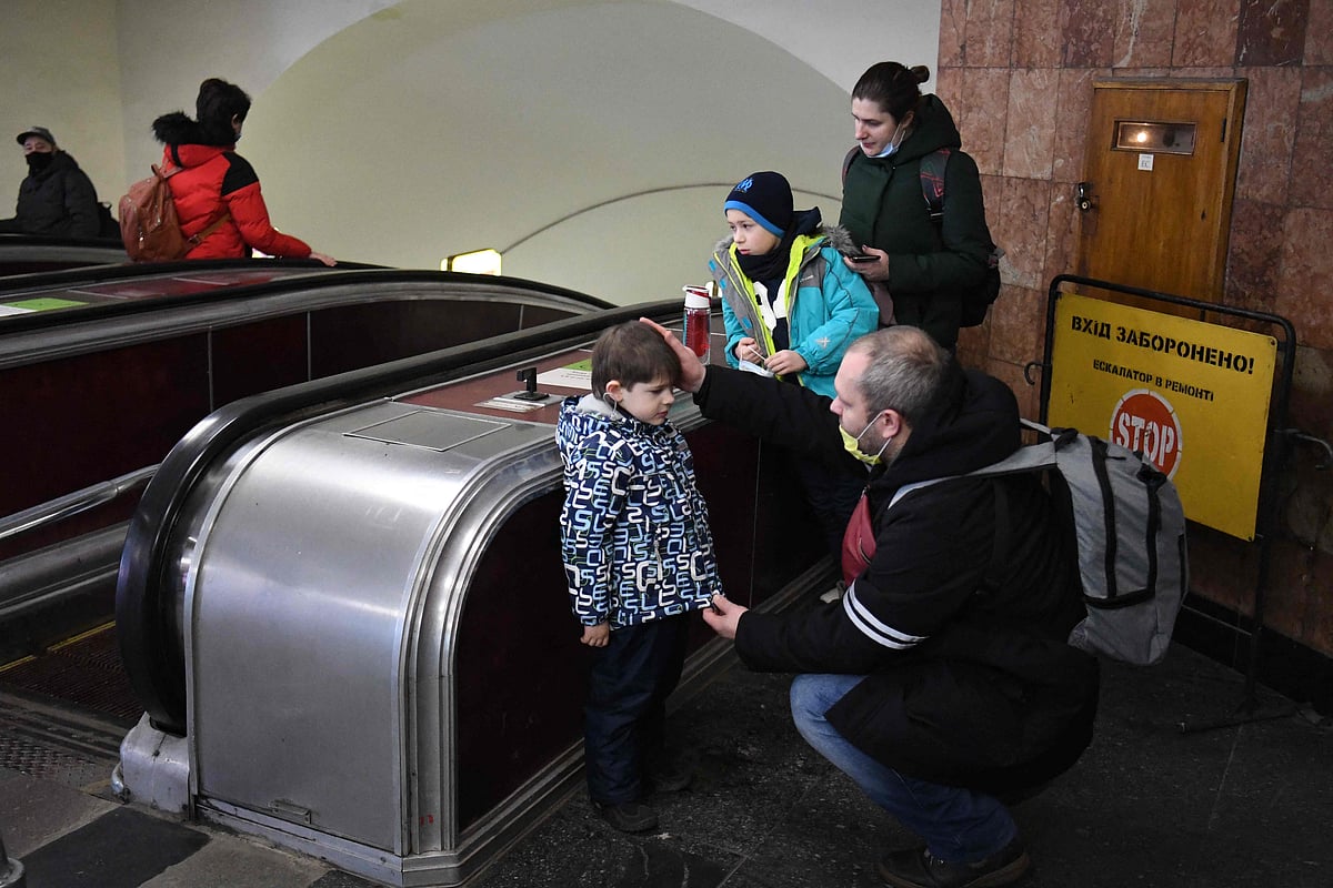 Alexander (R), reassures his son as the family takes refuge in a metro station in Kyiv in the morning of February 24, 2022. 