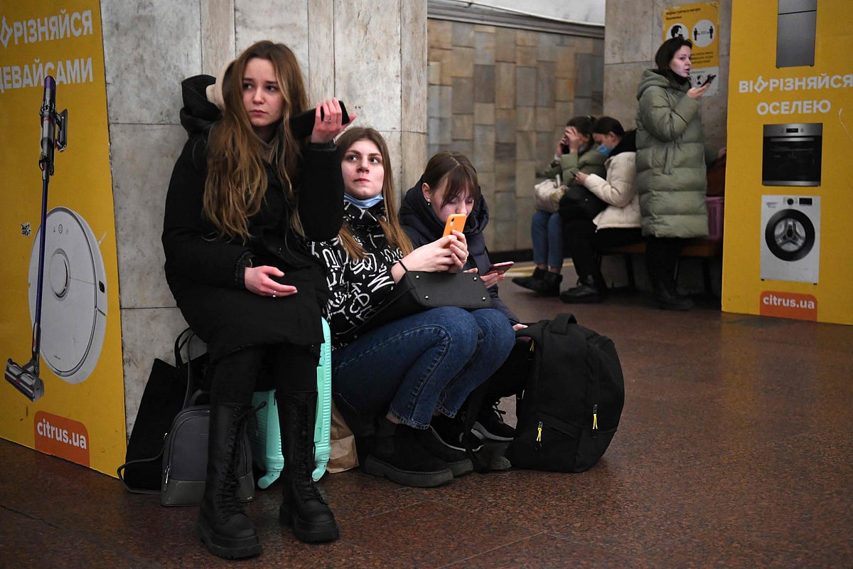 Girls hold their mobile phone as they take refuge in a metro station in Kyiv in the morning of February 24, 2022. 