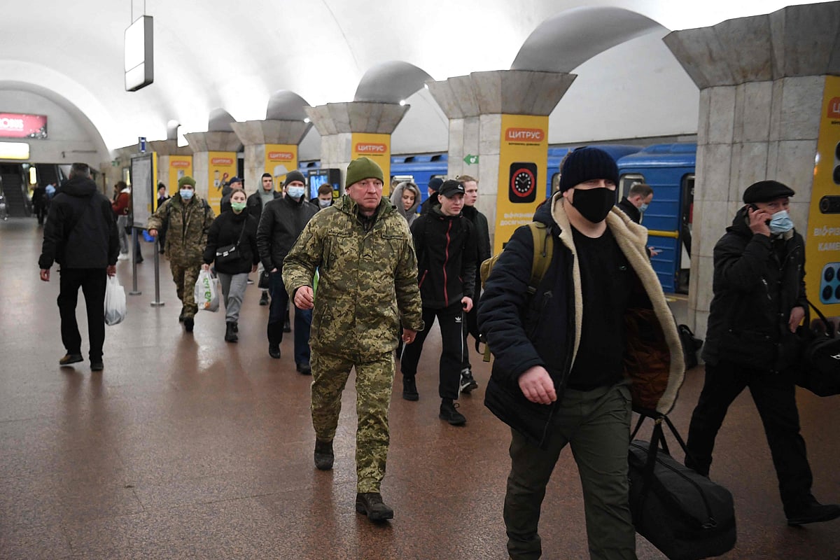 People, some carrying bags and suitcases, walk in a metro station in Kyiv early on February 24, 2022. 