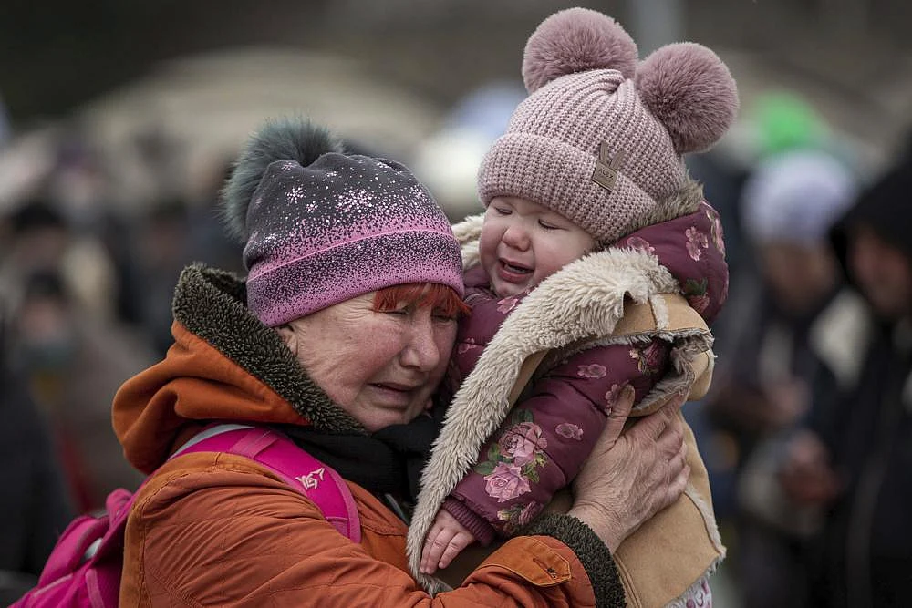 A woman holding a child cries after fleeing from the Ukraine and arriving at the border crossing in Medyka, Poland, on Monday | AP