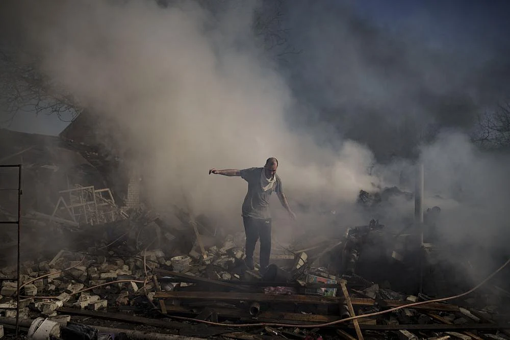 A man walks on the debris of a burning house, destroyed after a Russian attack in Kharkiv, Ukraine, Thursday, March 24, 2022 | AP