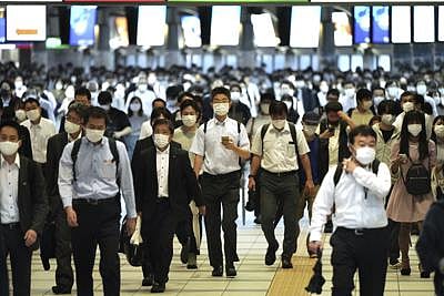 Commuters wearing face masks walk in a passageway during a rush hour at Shinagawa Station Friday, Oct. 1, 2021, in Tokyo | AP