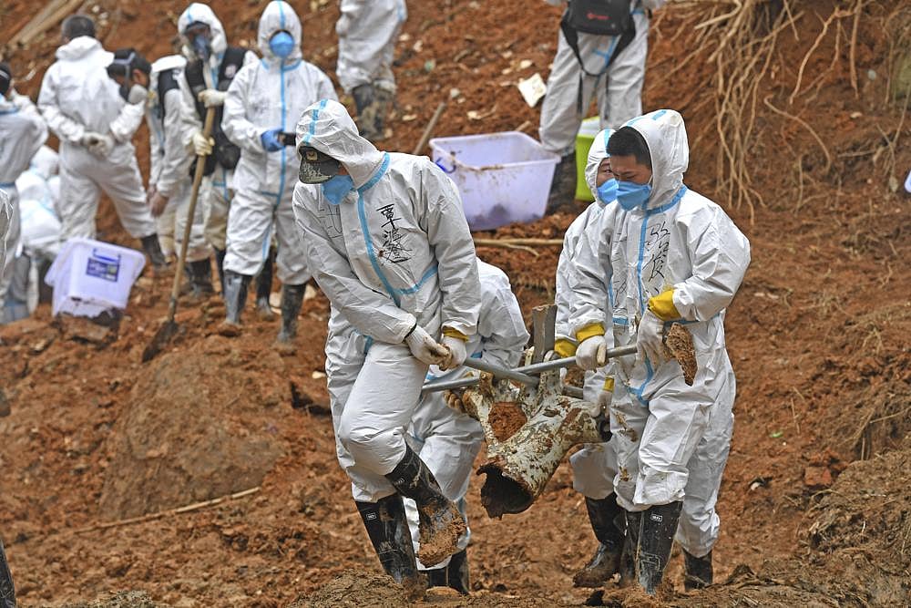 In this photo released by Xinhua News Agency, rescuers carry a piece of plane wreckage at the site of Monday's plane crash in Tengxian County, southern China's Guangxi Zhuang Autonomous Region, on March 25, 2022 | AP