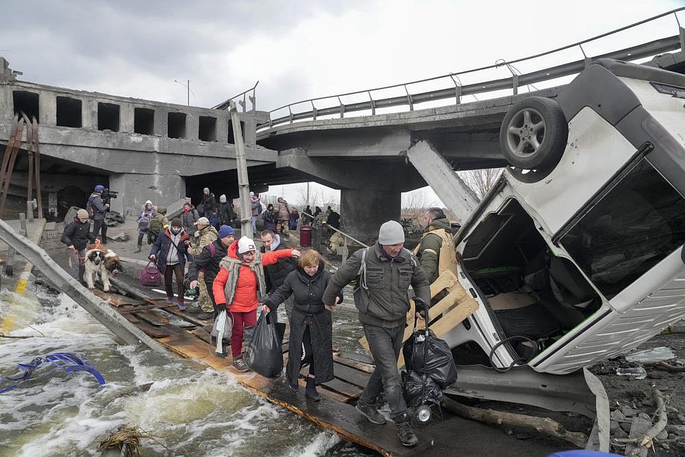 People cross an improvised path under a destroyed bridge while fleeing the town of Irpin close to Kyiv, Ukraine, on Monday | AP