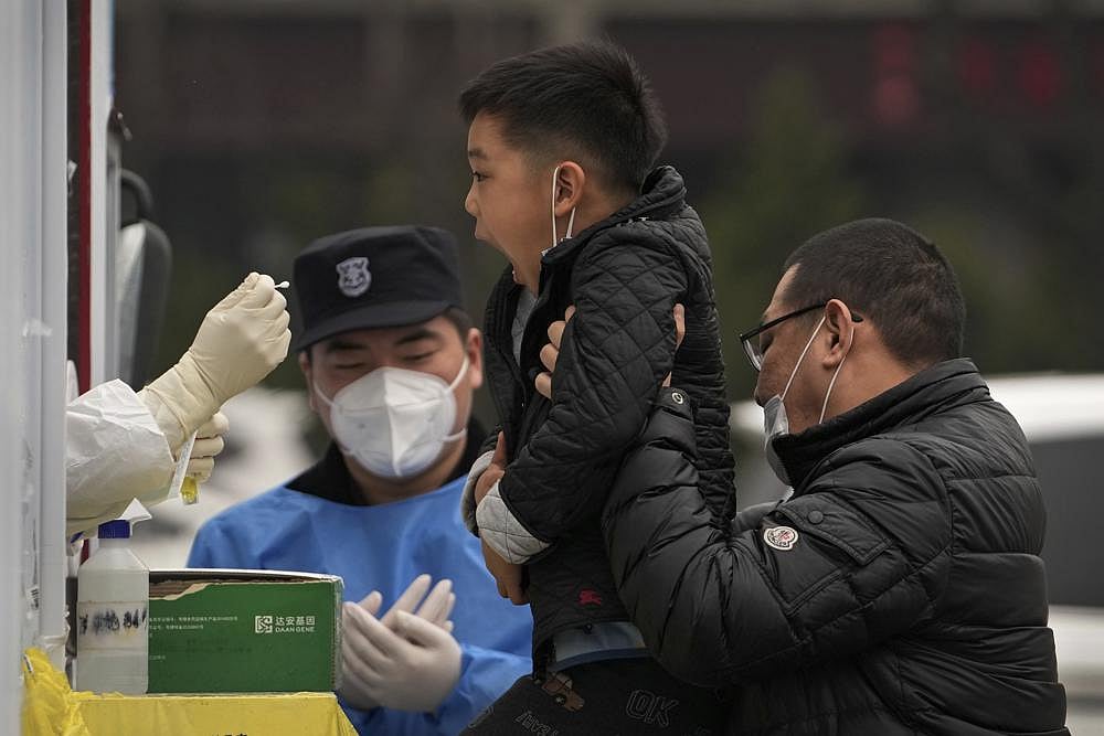 A man lifts his child to get a COVID-19 test at a private mobile coronavirus testing facility, on Tuesday, March 29, 2022, in Beijing | AP