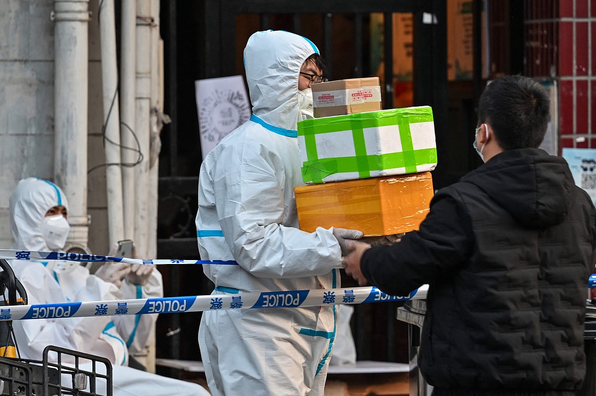 A delivery man delivers an order outside of a locked down neighbourhood after the detection of new cases of Covid-19 in Huangpu district, in Shanghai on March 15, 2022.