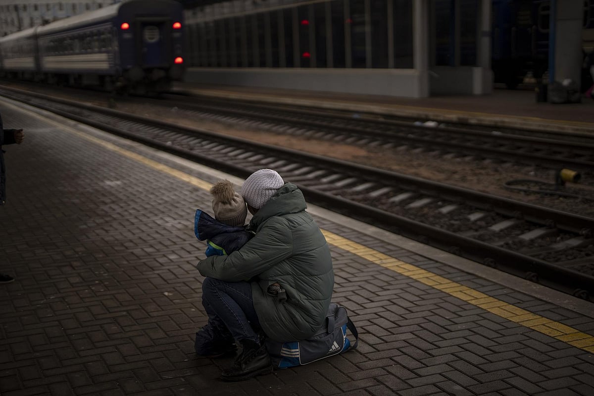 A woman with her son look at a train leaving as they try to flee at the Kyiv station, Ukraine, on Thursday
