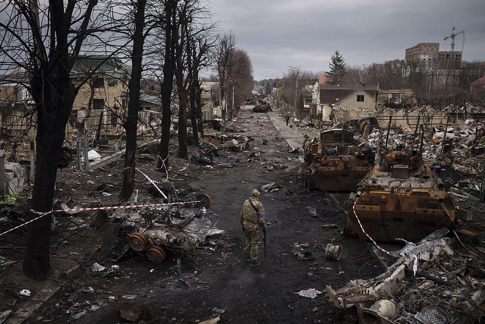 A Ukrainian serviceman walks amid destroyed Russian tanks in Bucha, on the outskirts of Kyiv, Ukraine, on Wednesday, April 6, 2022 | AP