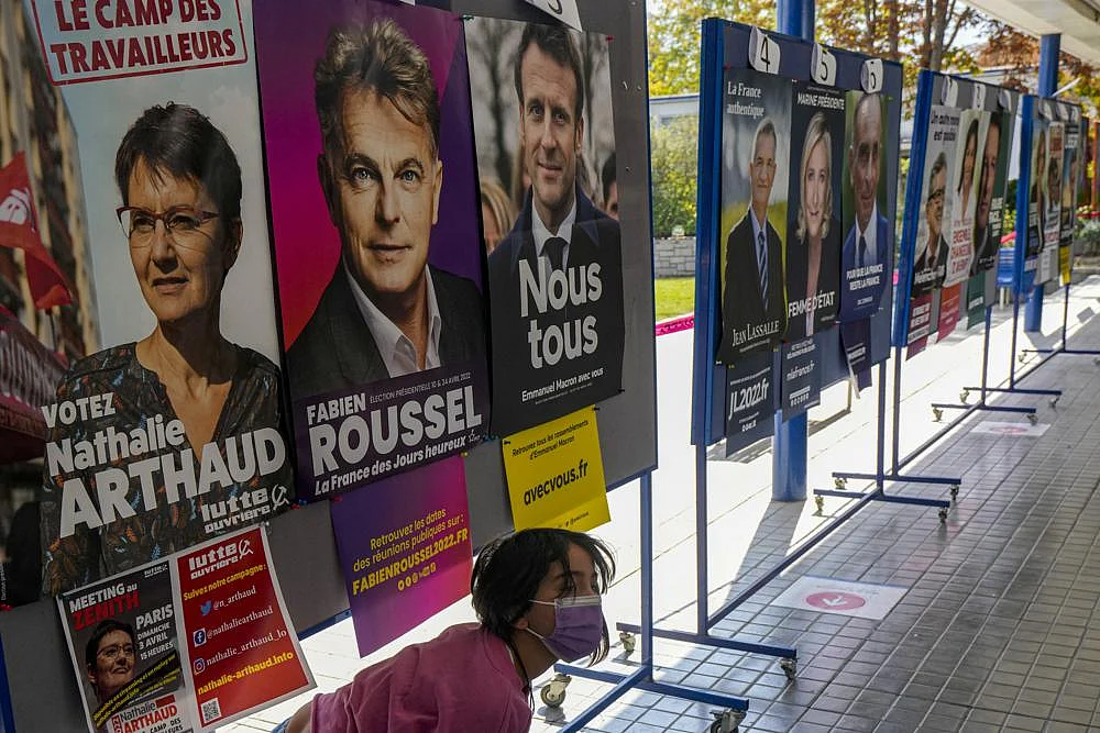 A girl walks past presidential campaign posters at a school working as a polling station for French citizens who living in Chile to vote one day ahead of France's general elections in Santiago, Chile, on Saturday, April 9, 2022 | AP