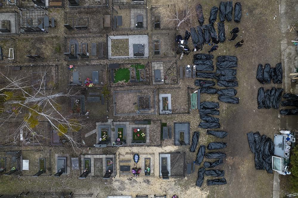 Policemen work to identify civilians who were killed during the Russian occupation in Bucha, Ukraine, on the outskirts of Kyiv, before sending the bodies to the morgue, on Wednesday, April 6, 2022 | AP