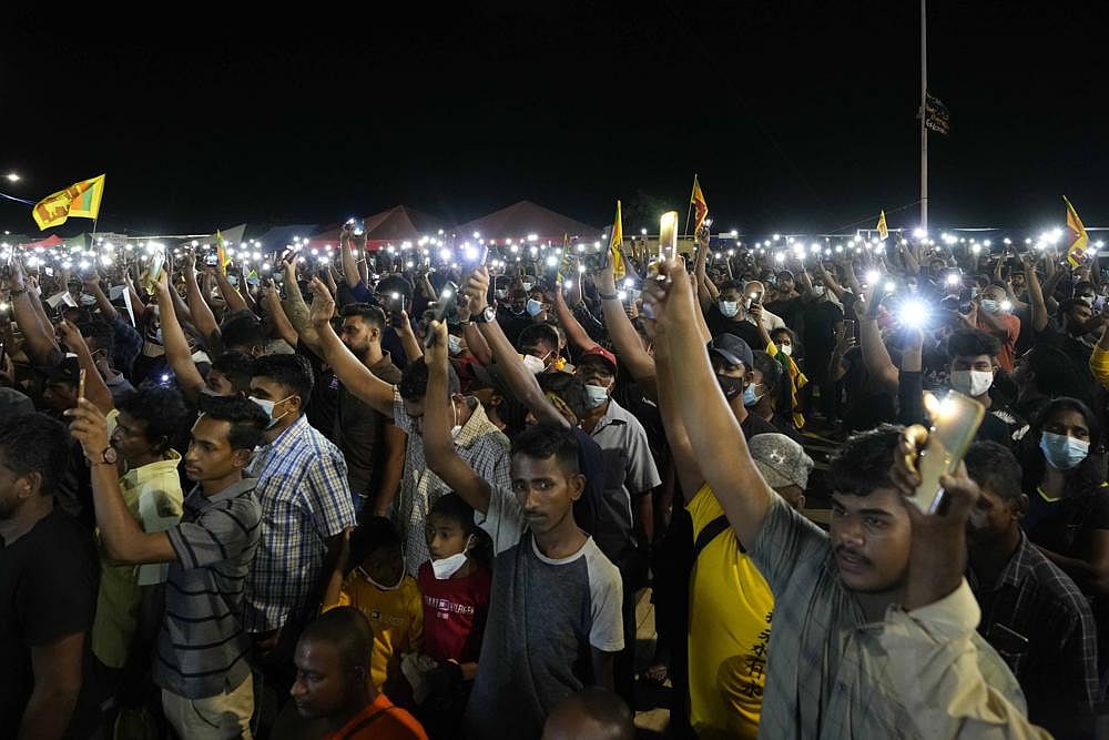 Sri Lankans hold up their mobile phone torches during a vigil condemning police shooting at protesters in Rambukkana, 90 kilometers northeast of Colombo, at a protest outside the president's office in Colombo, Sri Lanka, on Tuesday, April 19, 2022 | AP