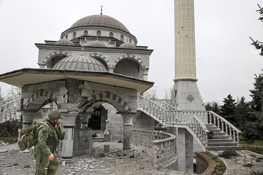 A serviceman of the Russian-backed Donetsk People's Republic militia walks past a damaged mosque during heavy fighting in an area controlled by Russian-backed separatist forces in Mariupol, Ukraine, on Tuesday, April 19, 2022 | AP