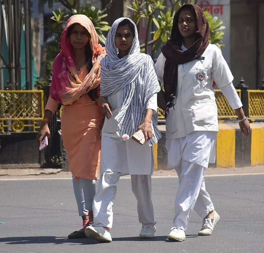 Health workers cross a road while fully covering their bodies in wake of scorching heat in Ujjain on Thursday. |  FP PHOTO