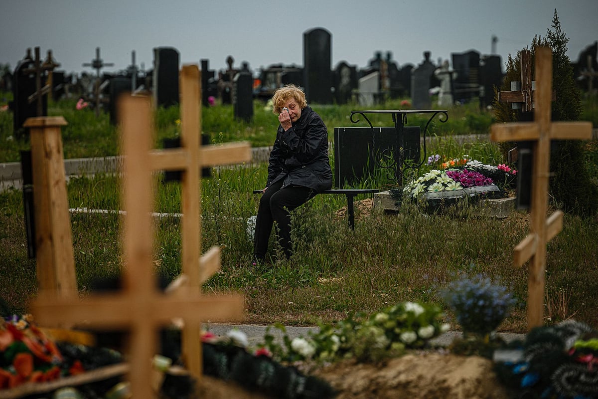 A woman mourns while visiting the grave of Stanislav Hvostov, 22, a Ukrainian serviceman killed during the Russian invasion of Ukraine, in the military section of the Kharkiv cemetery number 18 in Bezlioudivka, eastern Ukraine on May 21, 2022 | AFP