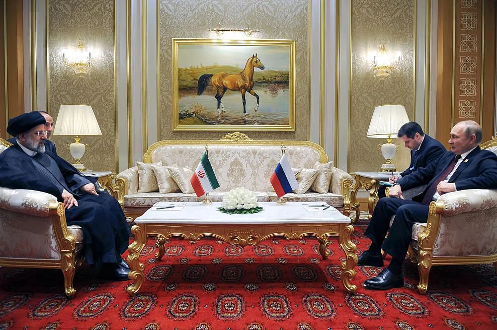 Russian President Vladimir Putin, right, speaks to Iran's President Ebrahim Raisi on the sideline of the summit of Caspian Sea littoral states in Ashgabat, Turkmenistan, on June 29 | AP