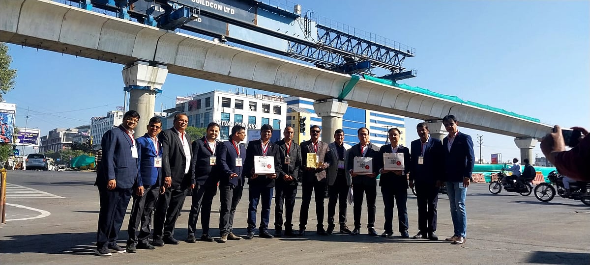 NRIs pose with ongoing construction work for metro