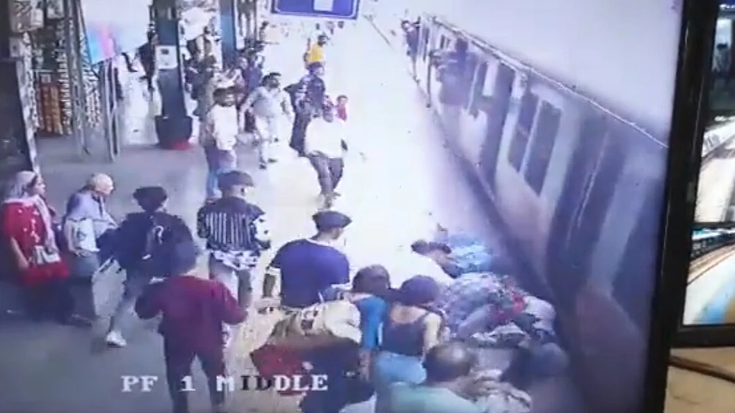 Still from the CCTV showing the woman (lying close to the local train) being pulled away in the nick of time | Twitter@Central_Railway