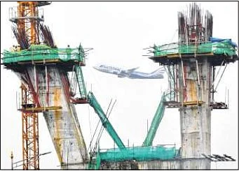 An aeroplane passes overhead as people work on the Santacruz Chembur Link Road Extension
project at Santacruz
