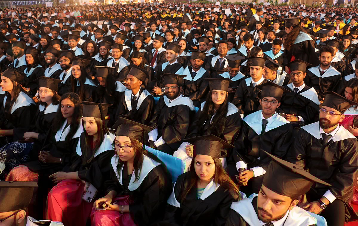 Students wearing convocation attire sit in chairs for their turn to come to receive their degree during IIM Indore convocation on Sunday.  