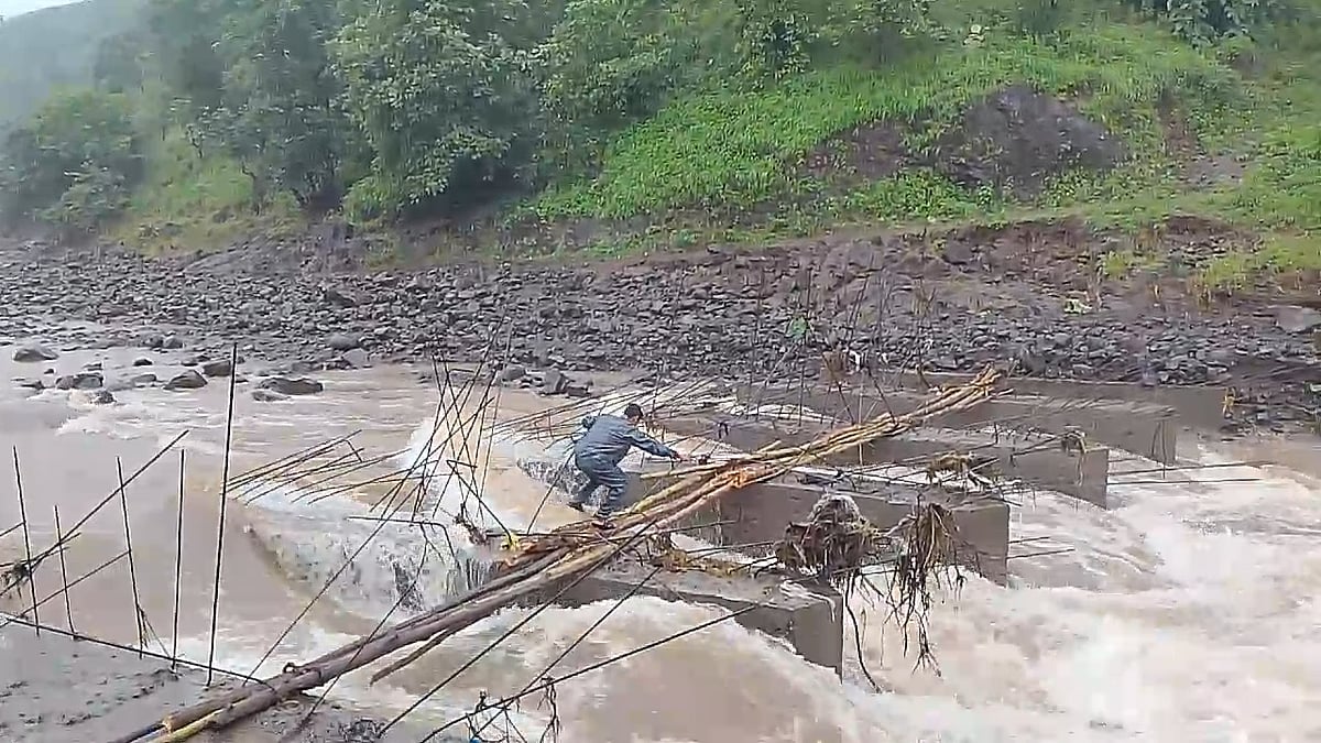 A villager attempting to cross under-construction culvert by improvising a bridge made of wooden planks over the flowing drain | FP Photo