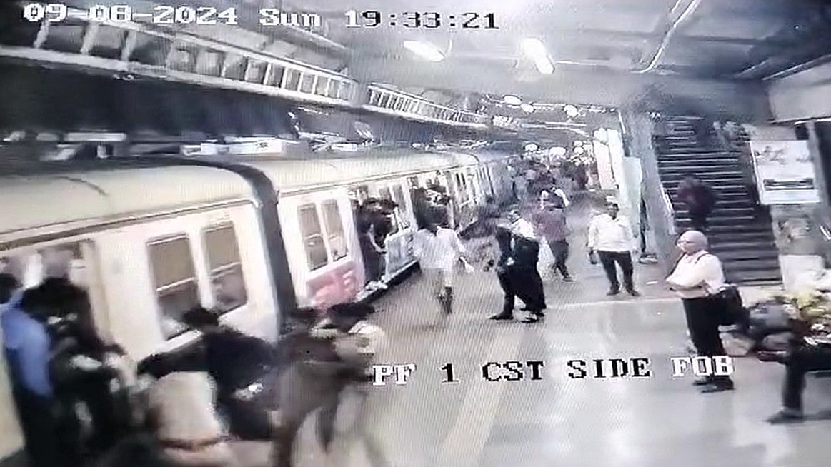 The police rescuing the man from falling in between the gap  | Screenshot of CCTV video Accessed By FPJ 