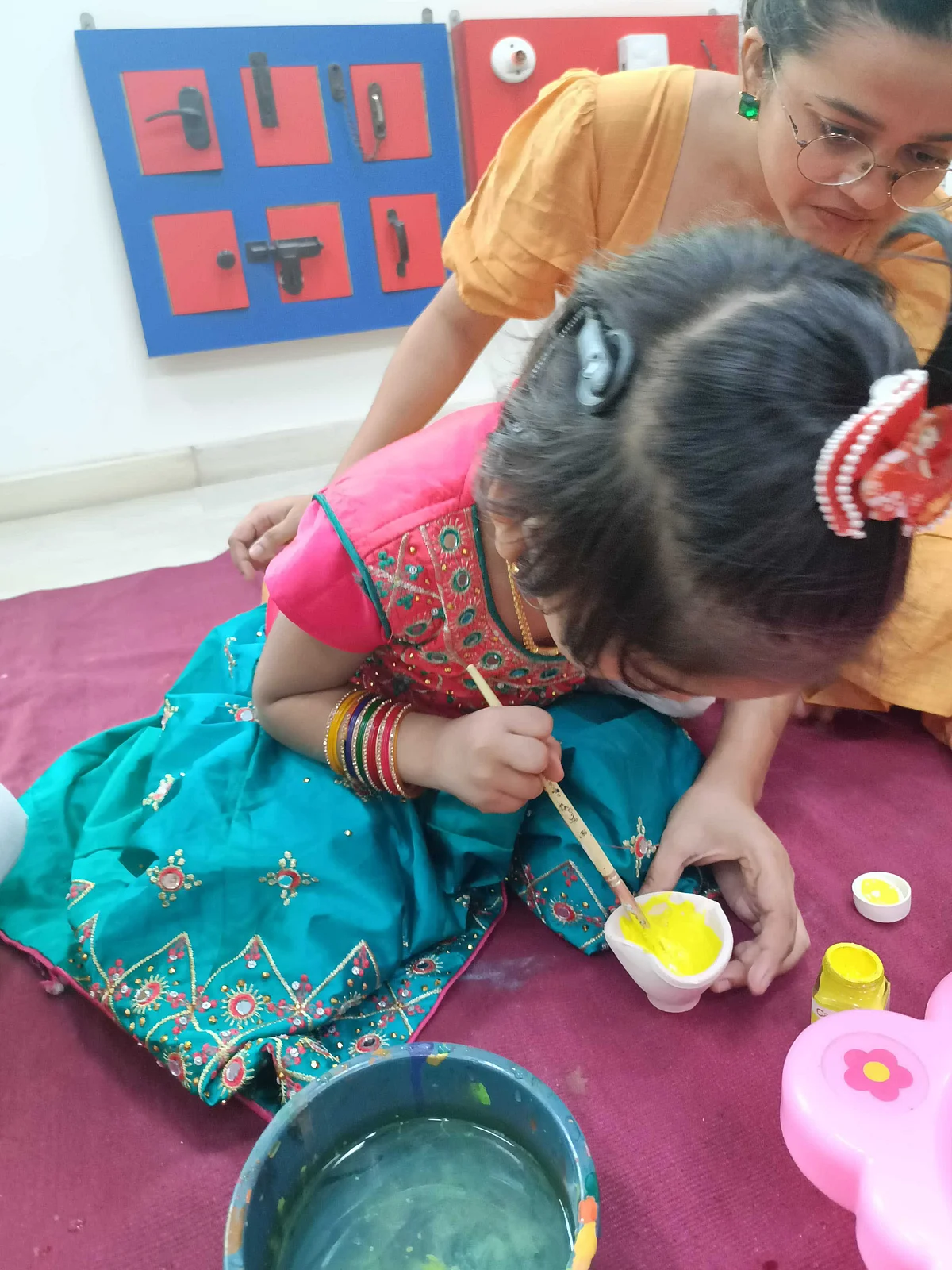 A child with cochlear implant paints a diya for Diwali celebration