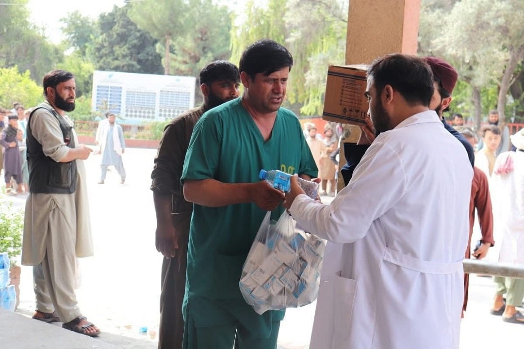 A healthcare worker distributes emergency medicine and water to medical teams amid a surge in casualties.