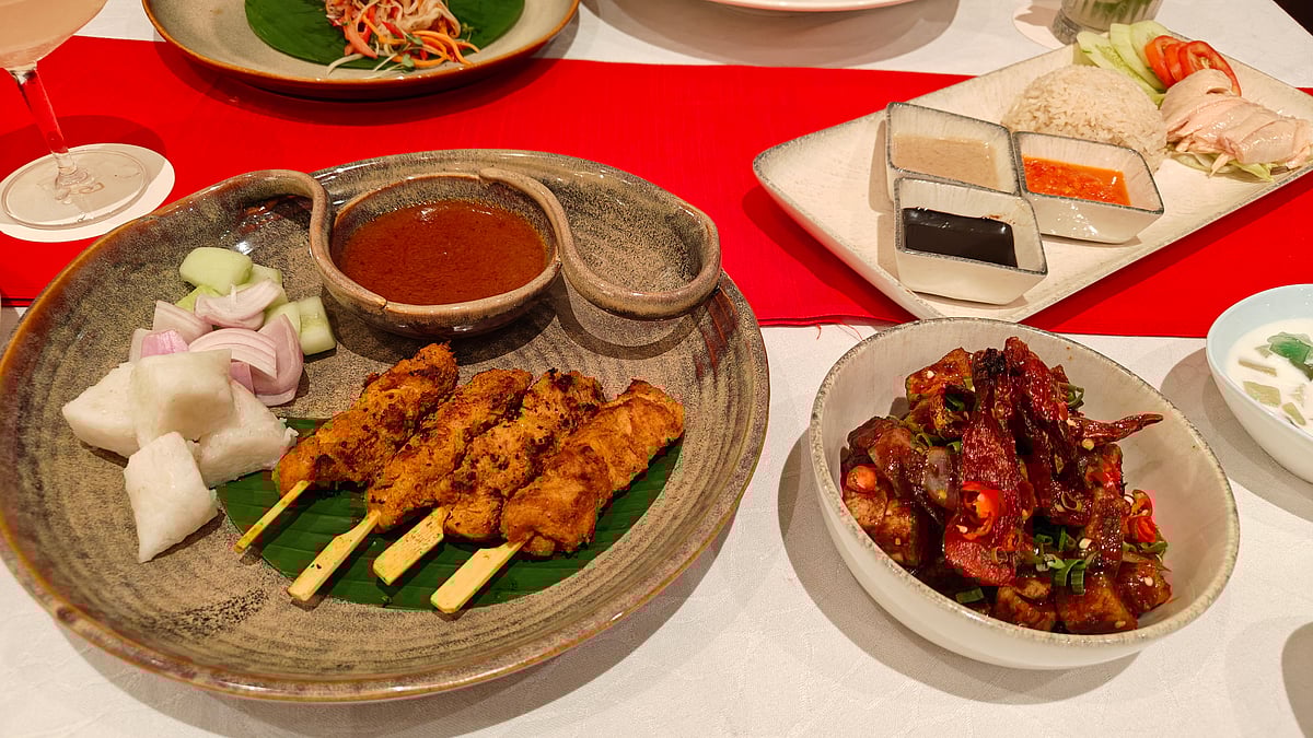 Chicken Satay served with peanut sauce, cucumber, chopped onions and rice cakes; (extreme right) chicken rice with ginger paste, chilly sauce, and dark-sweet soy sauce