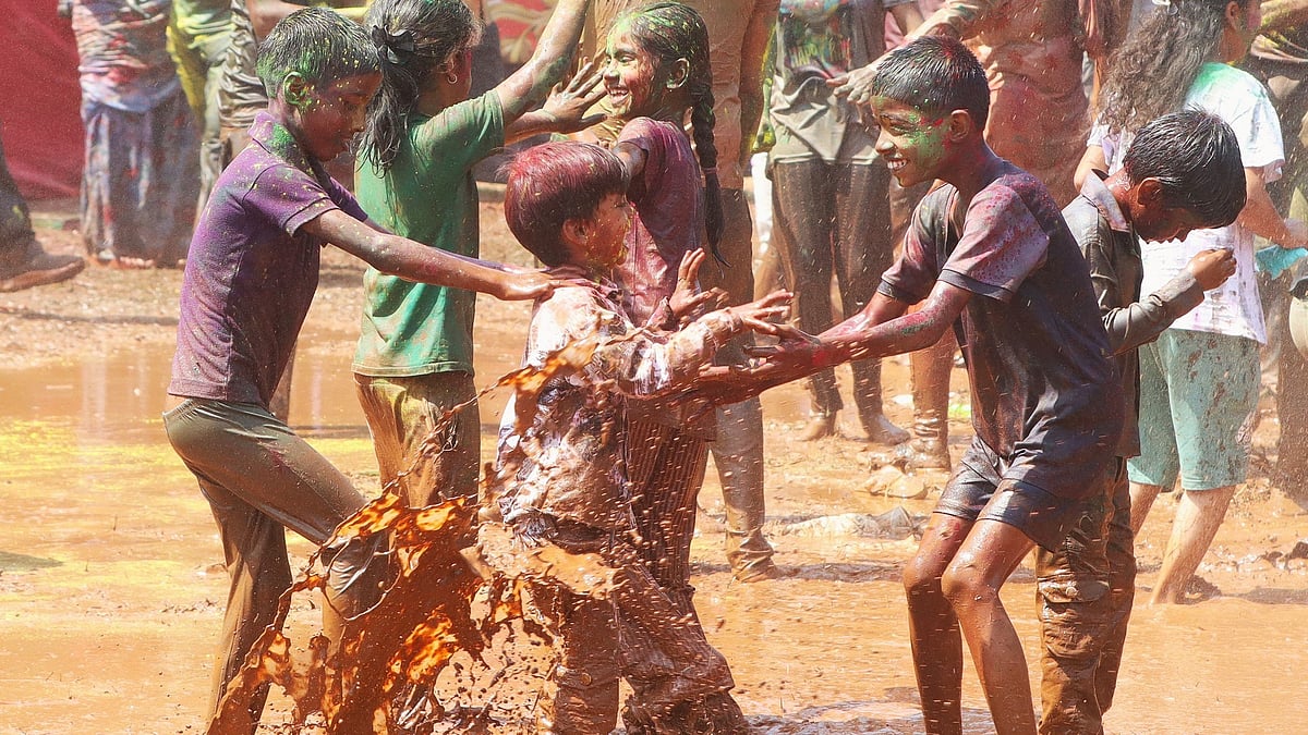 Children enjoy muddy water play, turning the ground into a splash-filled celebration.