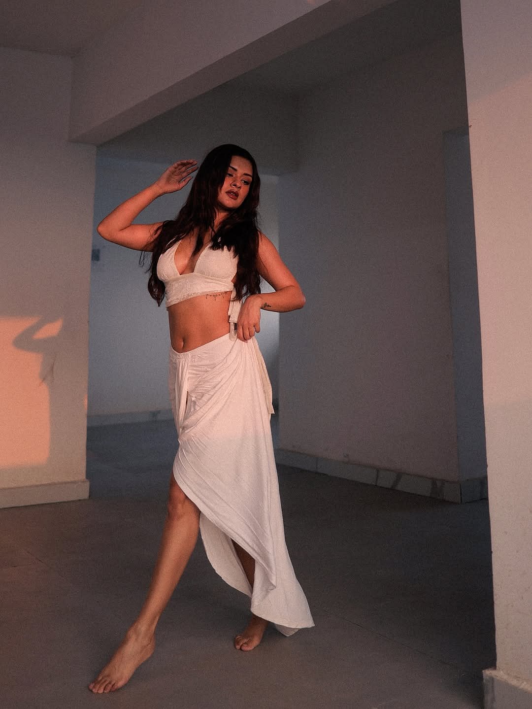 The wrap-style skirt with a thigh-high slit brings fluidity and movement, subtly elevating the overall silhouette.