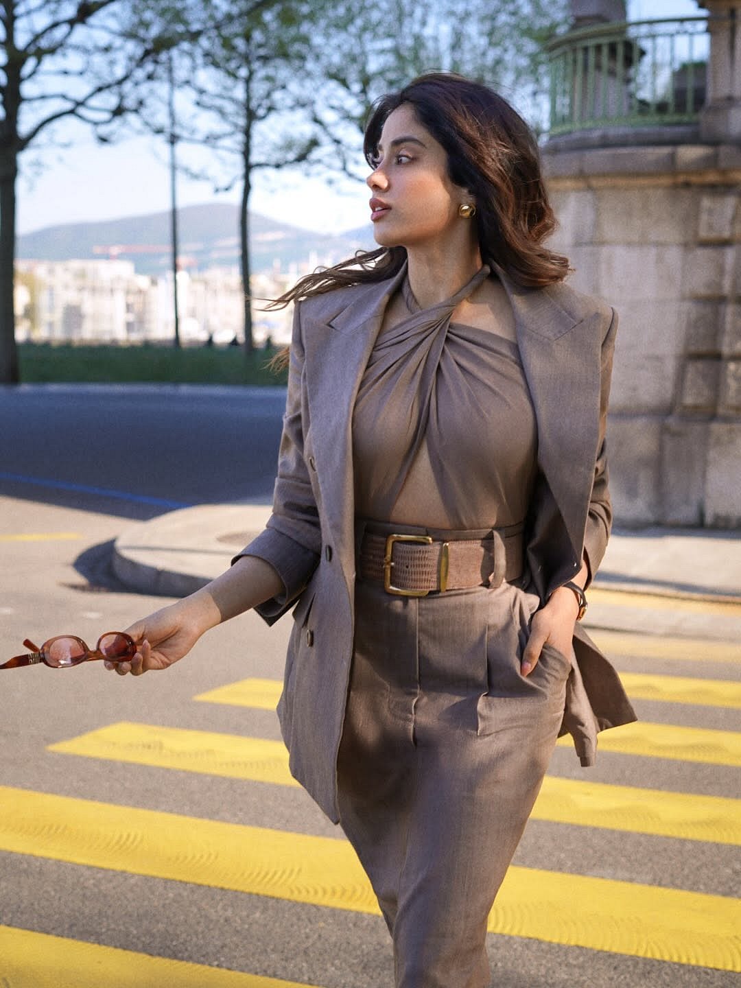The fitted midi skirt enhances her silhouette while a wide belt with a gold-toned buckle cinches the waist.