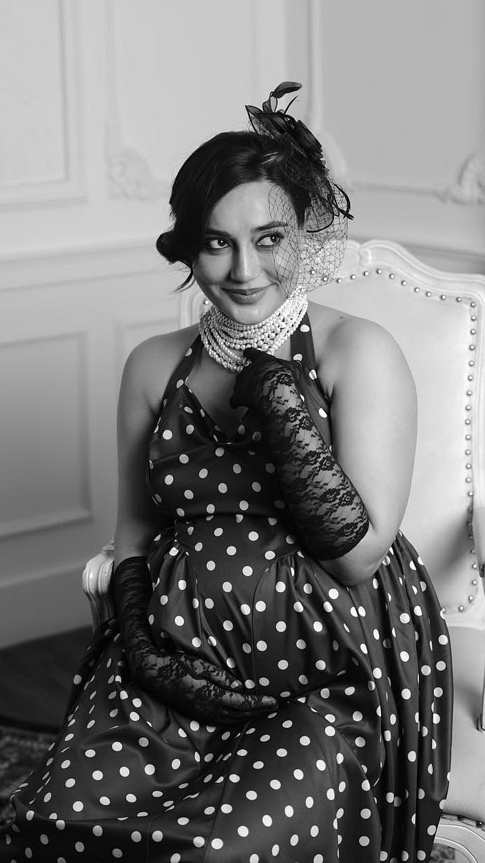Adding a touch of drama, she paired the outfit with delicate black lace gloves and a floral mesh hair accessory that perfectly complemented the vintage theme.