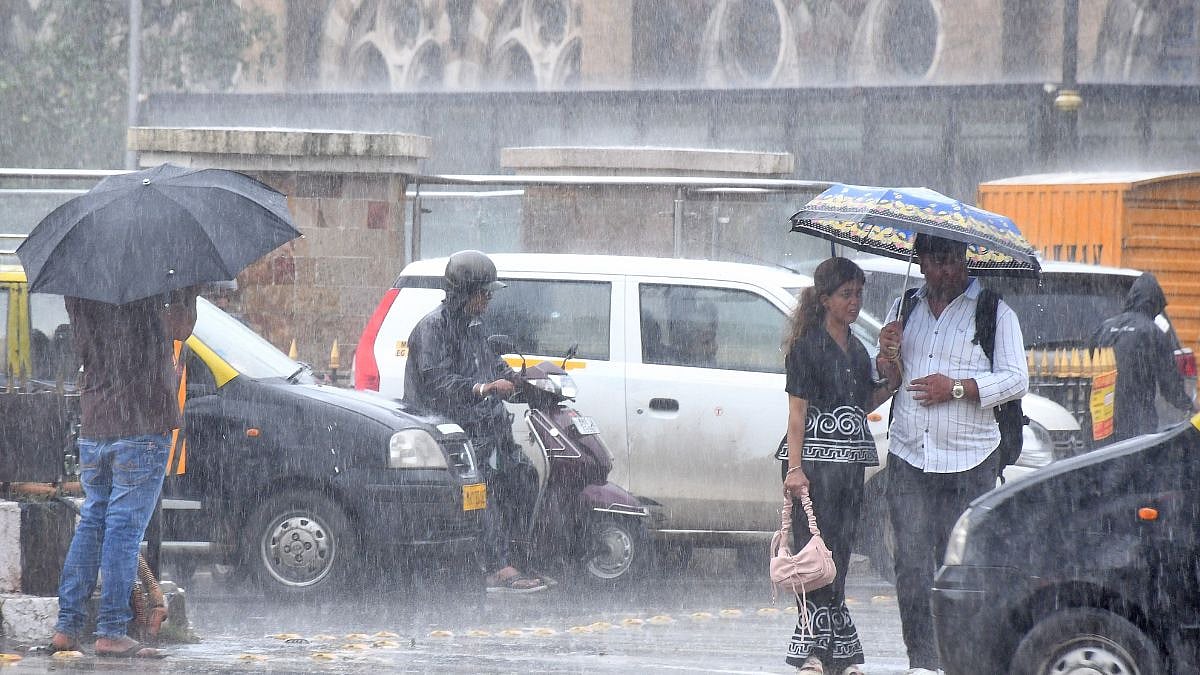 Pedestrians walk during the rain at CSMT in Mumbai