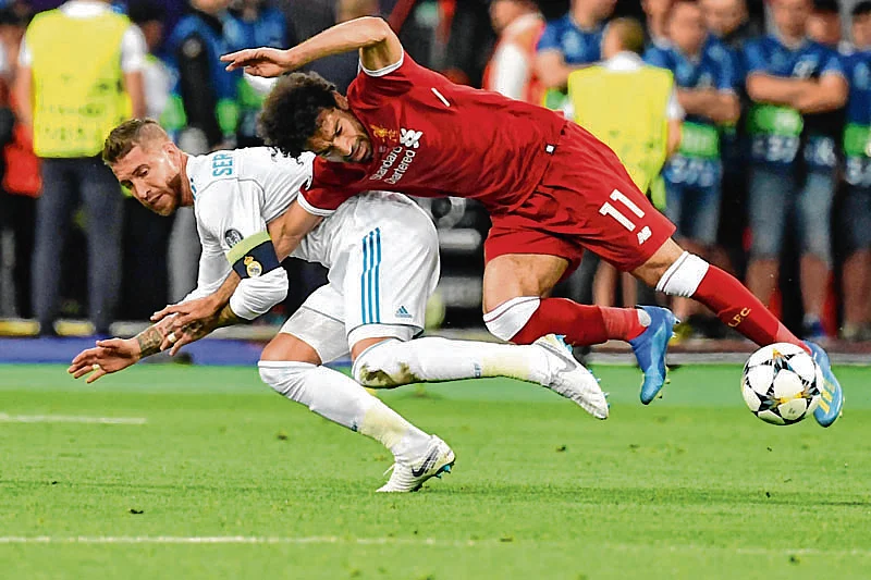 Liverpool's Egyptian forward Mohamed Salah (R) falls with Real Madrid's Spanish defender Sergio Ramos leading to Salah being injured during the UEFA Champions League final football match between Liverpool and Real Madrid at the Olympic Stadium in Kiev, Ukraine, on May 26, 2018.  | Pic/AFP