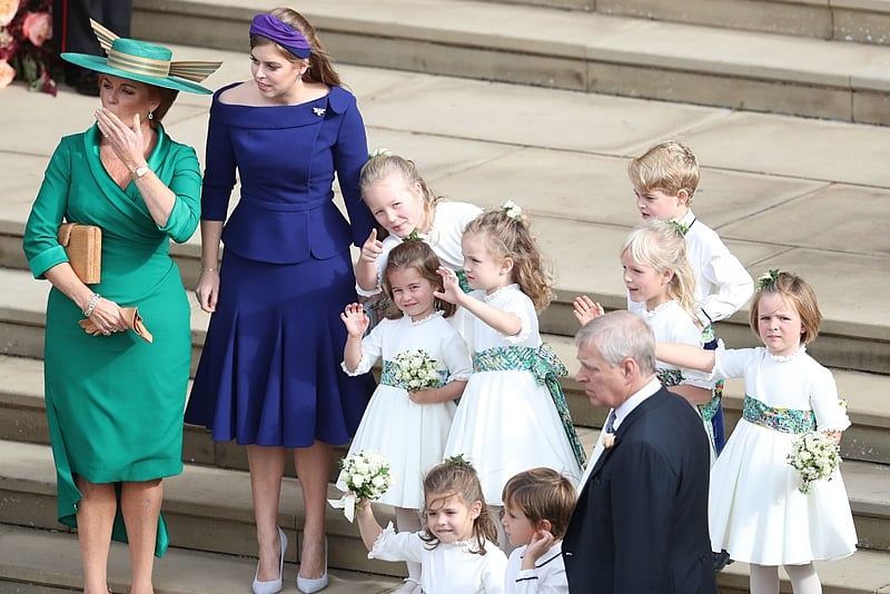 (L-R) Sarah, Duchess of York, Britain’s Princess Beatrice of York, bridesmaids including Savvanah Phillips, Princess Charlotte of Cambridge and Prince George of Cambridge (3R) wave off Britain’s Princess Eugenie of York and her husband Jack Brooksbank from the West Steps of St George’s Chapel, Windsor Castle, in Windsor, on October 12, 2018 after their wedding ceremony. (Photo by Andrew Matthews / POOL / AFP)