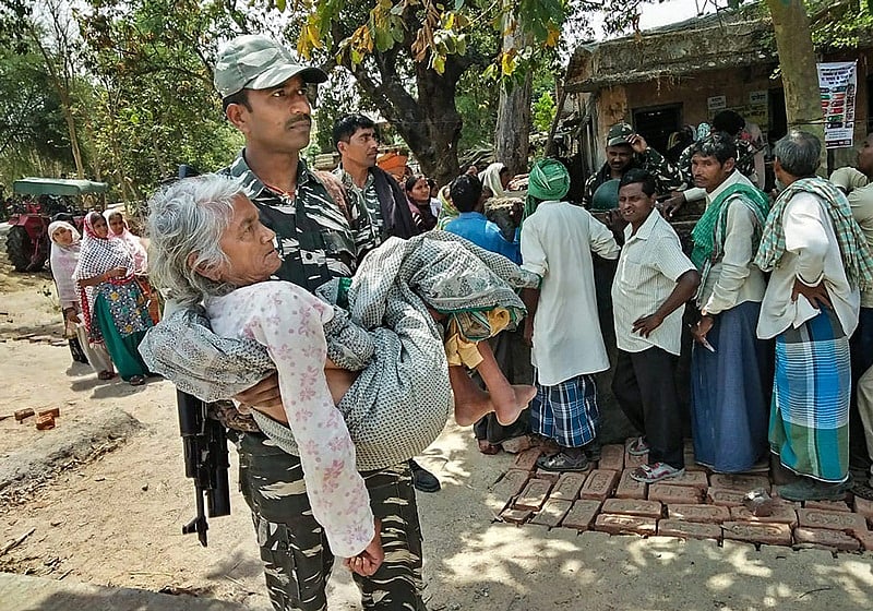 Gaya: A CRPF personnel carries an elderly woman to a polling station during the first phase of the general elections, in Gaya, Thursday, April 11, 2019. (Handout/PTI Photo) (PTI4_11_2019_000112B)