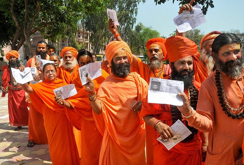Haridwar: Sadhus show their voter identity cards as they stand in a queue to cast their vote during the first phase of the general elections, at a polling station in Haridwar, Thursday, April 11, 2019. (PTI Photo)(PTI4_11_2019_000115B)
