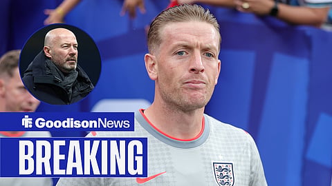 Jordan Pickford concentrates ahead of a game at the World Cup while wearing an England training shirt. To the left of him is a circle with Alan Shearer in it.