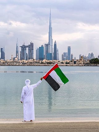 Emirati waving the UAE flag in front of Burj Khalifa Dubai