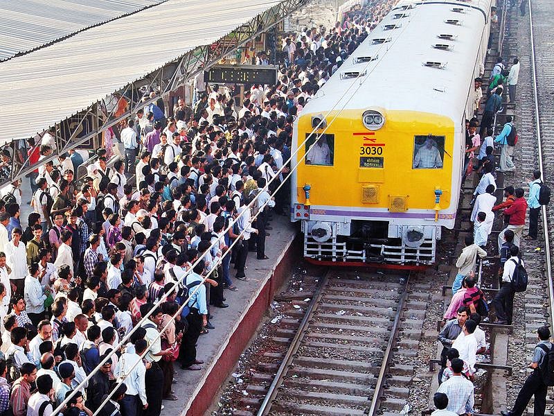 Indian commuters wait on an over-crowded platform to board a local train at a suburb railway station in Mumbai