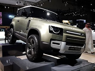 A Land Rover Defender 90 is displayed at a Motor Show. 