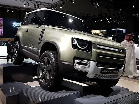 A Land Rover Defender 90 is displayed at a Motor Show. 