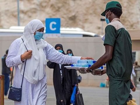 A pilgrim receiving a bottle of water upon arrival at Mount Arafat from a volunteer near Mecca. 